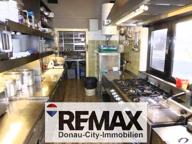 Professionelle Großküche mit Gasherd, Fritteuse, Edelstahlarbeitsflächen und gefliesten Wänden für den Restaurantbetrieb.