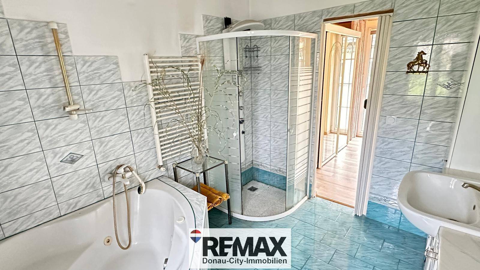 Badezimmer mit Eckbadewanne, Duschkabine und hellblauen Fliesen im 80er-Jahre-Stil.