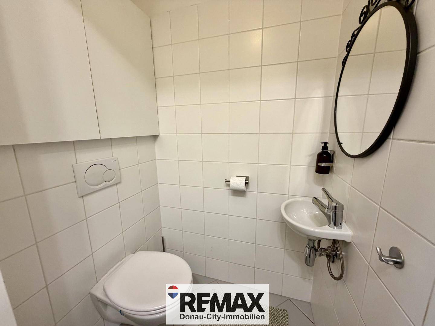 Kleines Gäste-WC mit Wand-WC und Handwaschbecken, hell gefliest und funktional.