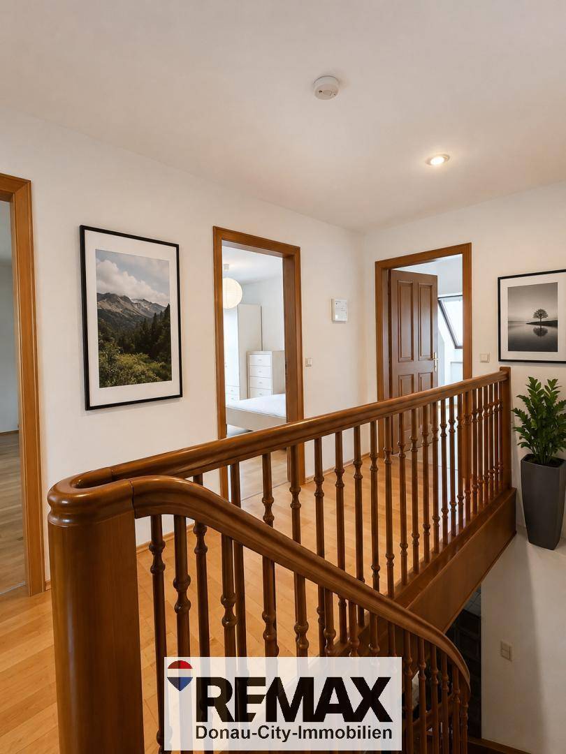 Heller Flur im Obergeschoss mit Holzgeländer und Blick in angrenzende Zimmer.