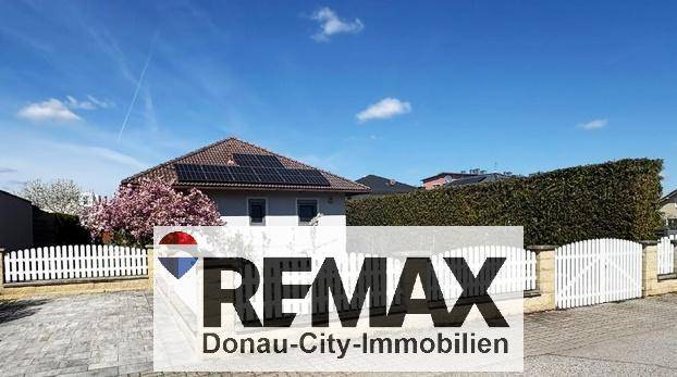 Das Haus von der Straße aus gesehen, mit weißem Zaun und Solaranlage auf dem Dach.