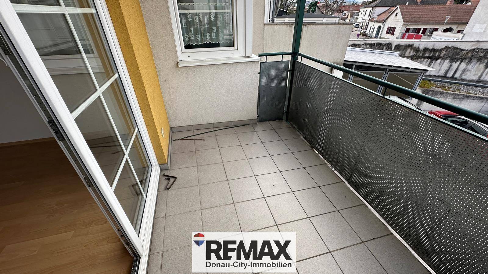 Außenbalkon mit Fliesenboden und Blick auf die Nachbarschaft und die umliegenden Dächer.