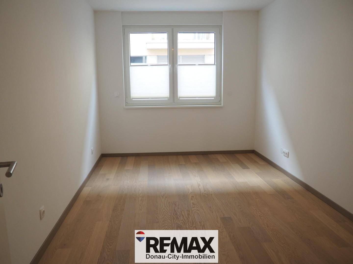 Gemütliches Schlafzimmer mit Holzboden und Fenster, bietet viel Tageslicht.