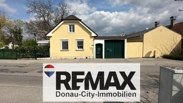 Vorderansicht des Hauses von der Straße mit gelber Fassade und integrierter Garage.