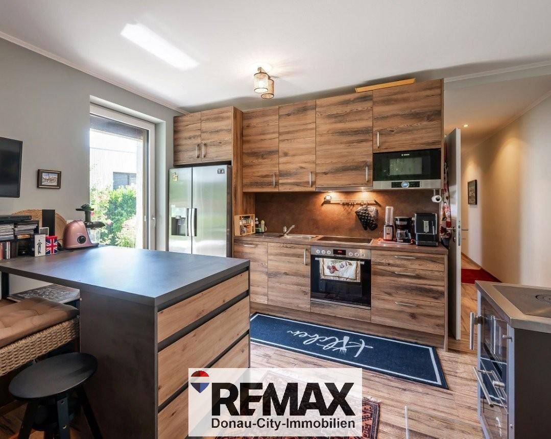 Funktionale Holzküche mit modernen Geräten, integriertem Essbereich und Zugang zum Außenbereich.