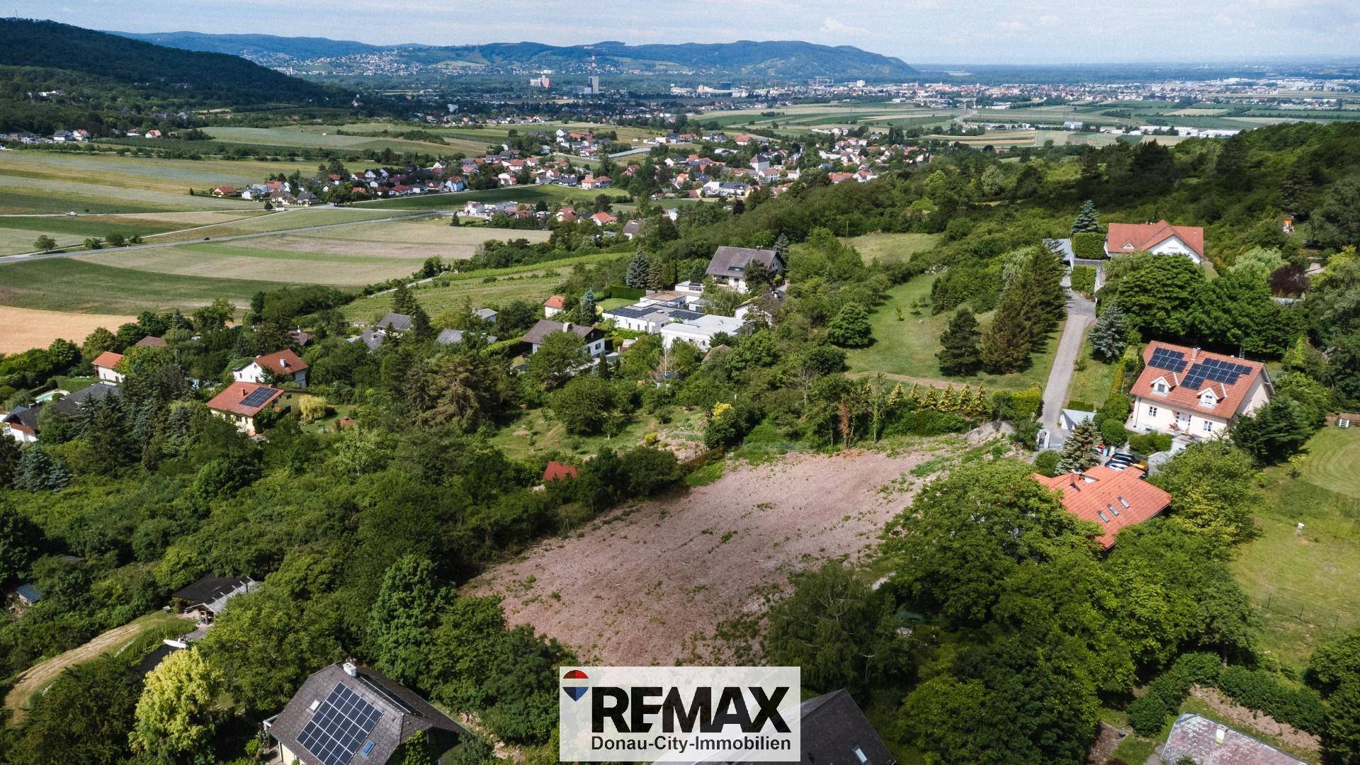 Panoramische Luftaufnahme einer idyllischen Wohnsiedlung mit weitem Blick auf Berge und Felder.
