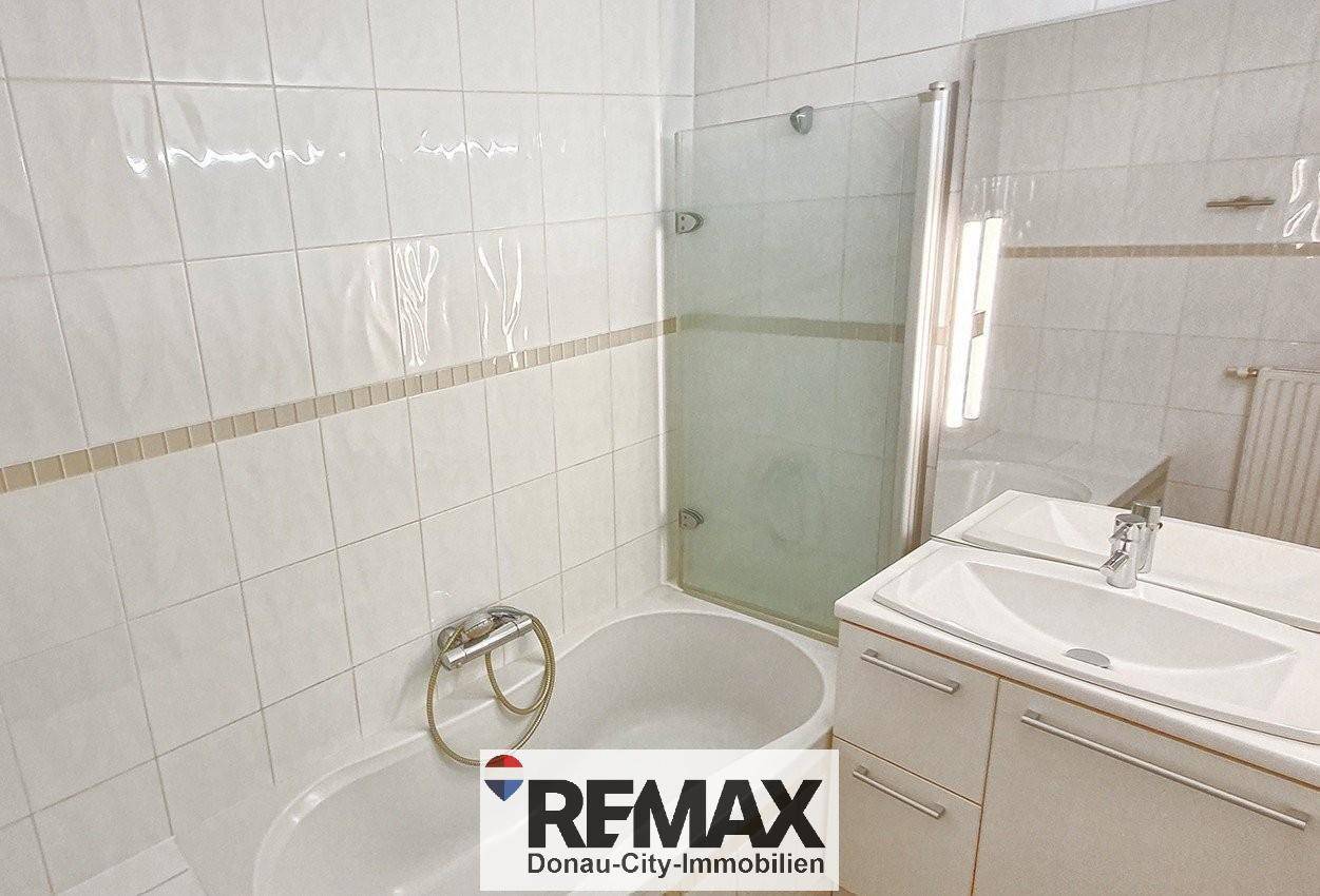 Badezimmer mit Badewanne, Duschkabine und Waschbecken, ausgestattet mit weißen Fliesen.