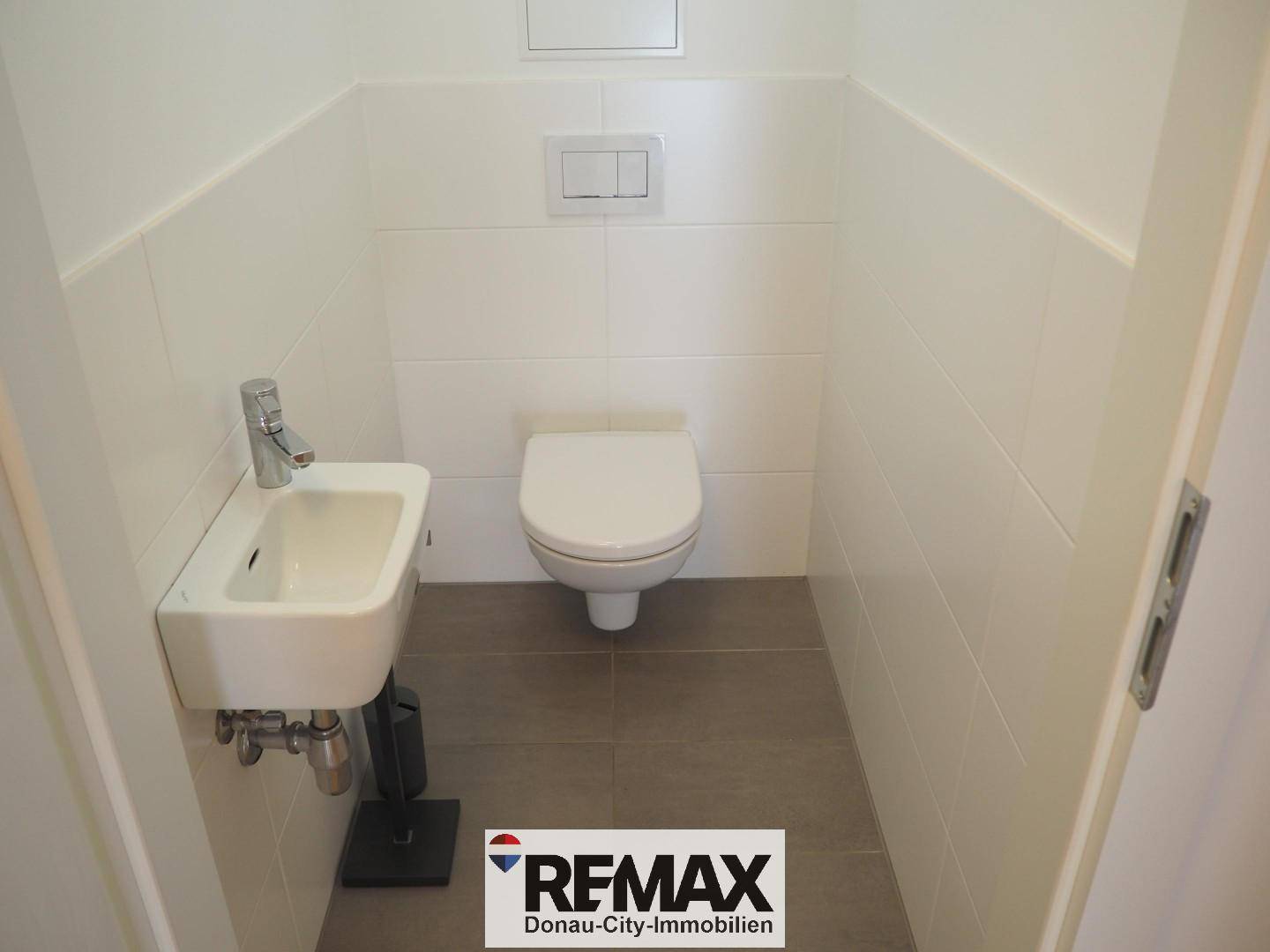 Separates WC mit wandhängendem WC und kleinem Handwaschbecken.