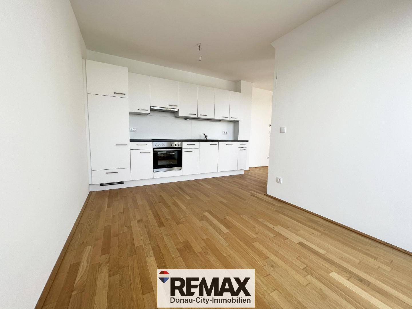 Moderne Einbauküche mit weißen Schränken, dunkler Arbeitsplatte und integrierten Geräten.