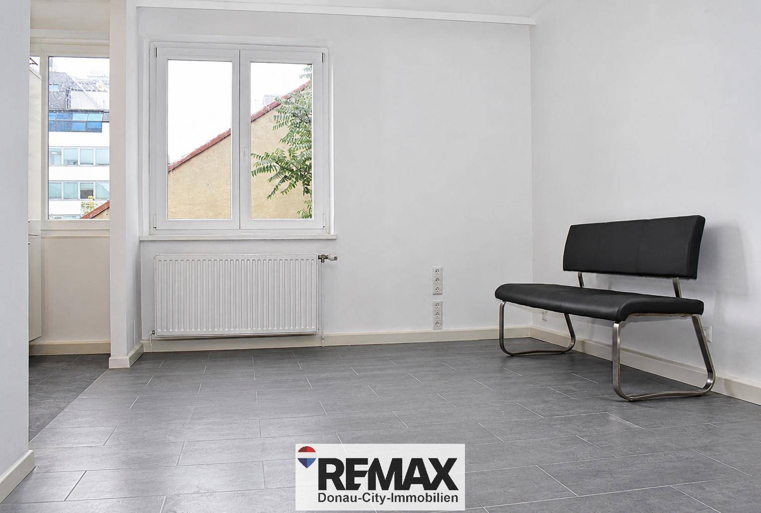 Heller Wohnraum mit großen Fenstern und Fliesenboden, bereit zur individuellen Gestaltung und Einrichtung.