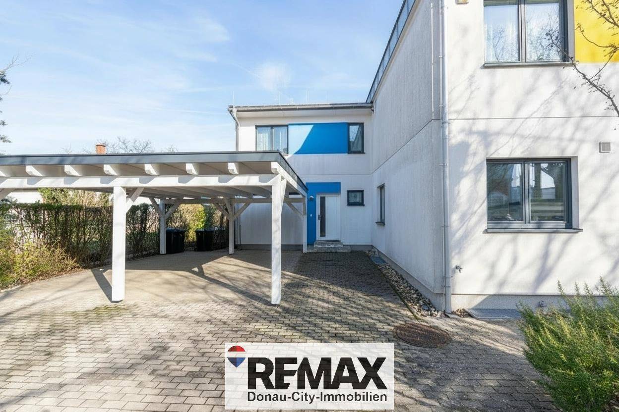 Vorderseite des Hauses mit Carport und gepflasterter Einfahrt.