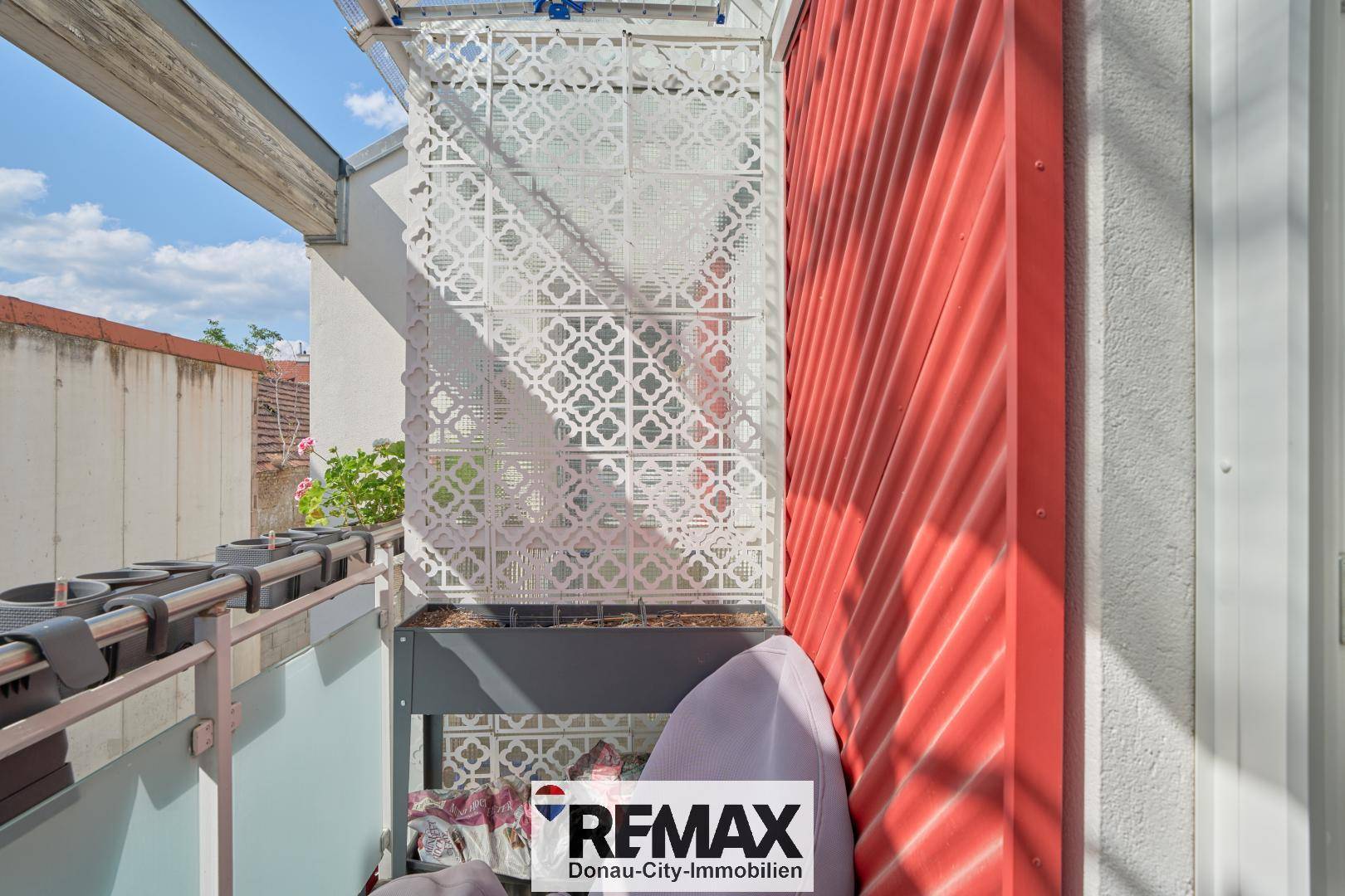 Kleiner Balkon mit dekorativen Elementen und Sichtschutz.