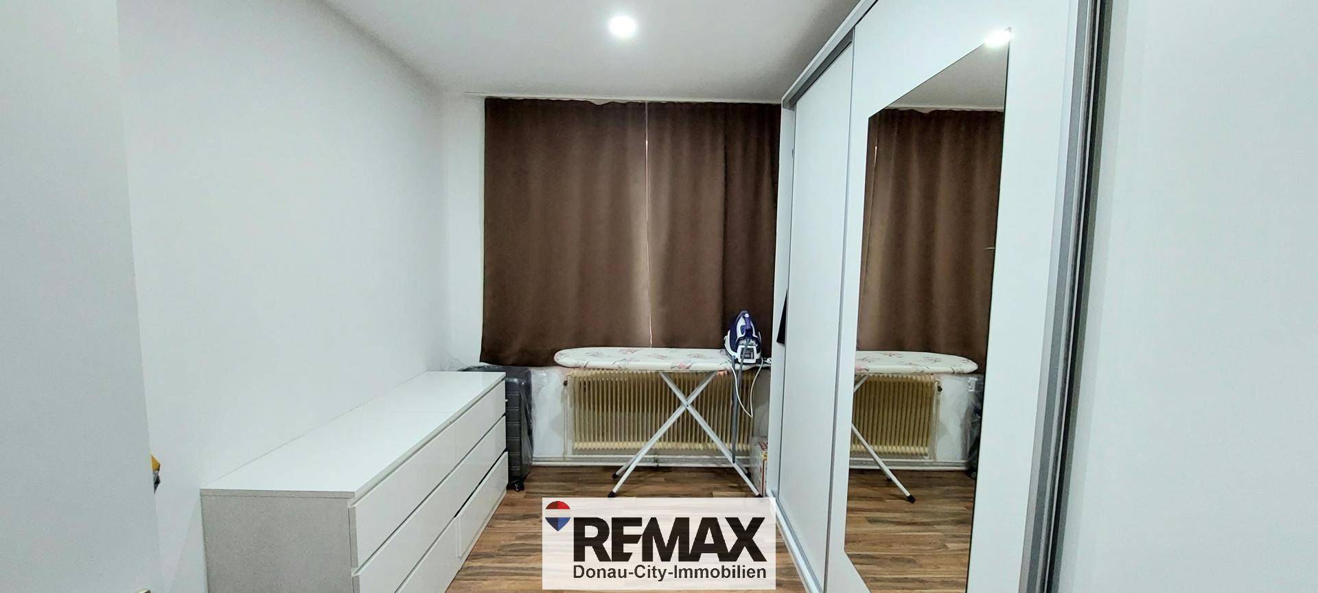 Raum mit Bügelbrett und Kommode, möglicherweise ein Ankleidezimmer oder Hauswirtschaftsraum.
