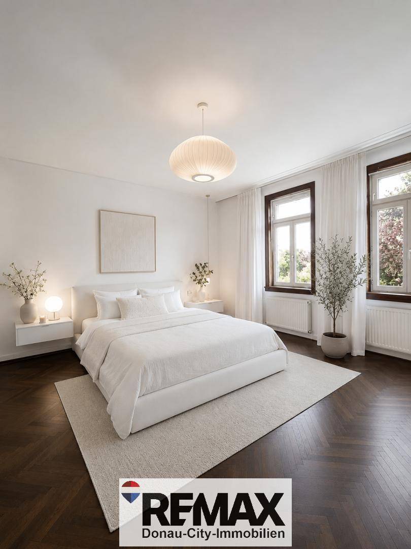 Helles Schlafzimmer mit großem Doppelbett, dunklem Fischgrätparkett und zwei Fenstern.