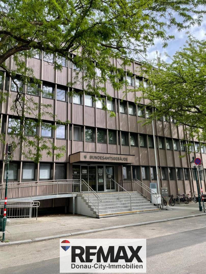 Ansicht eines Bundesamtsgebäudes mit moderner Fassade, Rampe und Treppenaufgang.