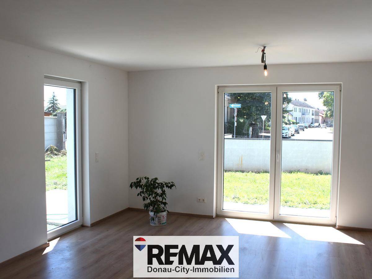 Heller Wohnraum mit großen Fenstern und Zugang zum Gartenbereich, ausgestattet mit Laminatboden.