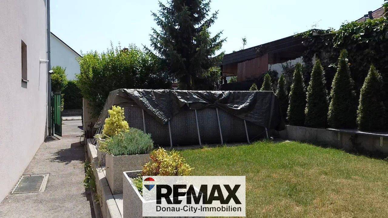 Gartenbereich mit Rasenfläche und einem abgedeckten Aufstellpool.