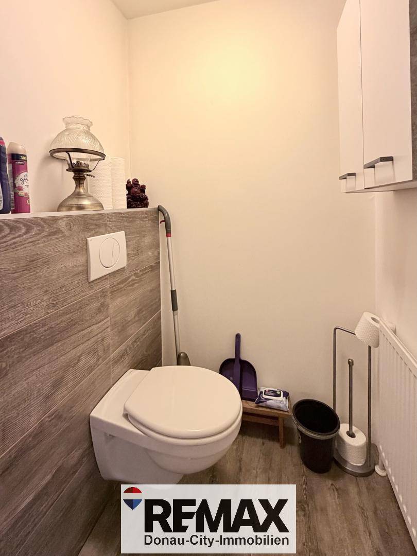 Modernes Gäste-WC mit wandhängender Toilette und Holzoptik-Fliesen an der Wand.