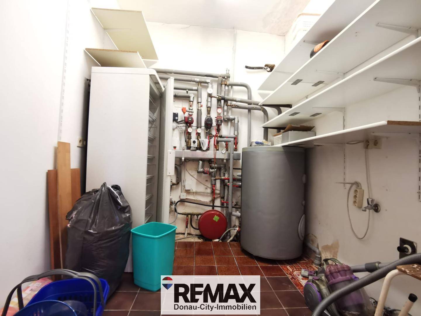Technikraum mit Heizungsanlage, Warmwasserspeicher und praktischen Regalen.