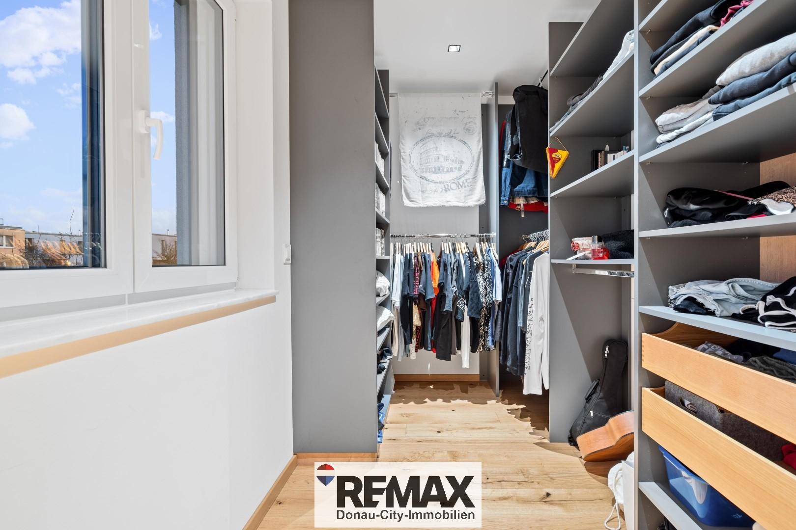 Begehbarer Kleiderschrank mit Regalen und Kleiderstangen, gut beleuchtet durch ein Fenster.