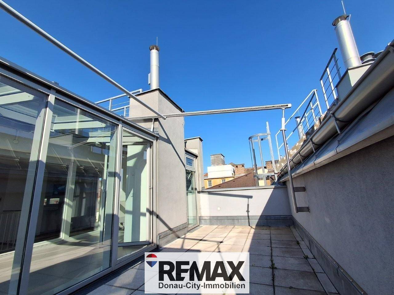 Geräumige Dachterrasse mit Glasanbau und weitem Blick, ideal für sonnige Tage.