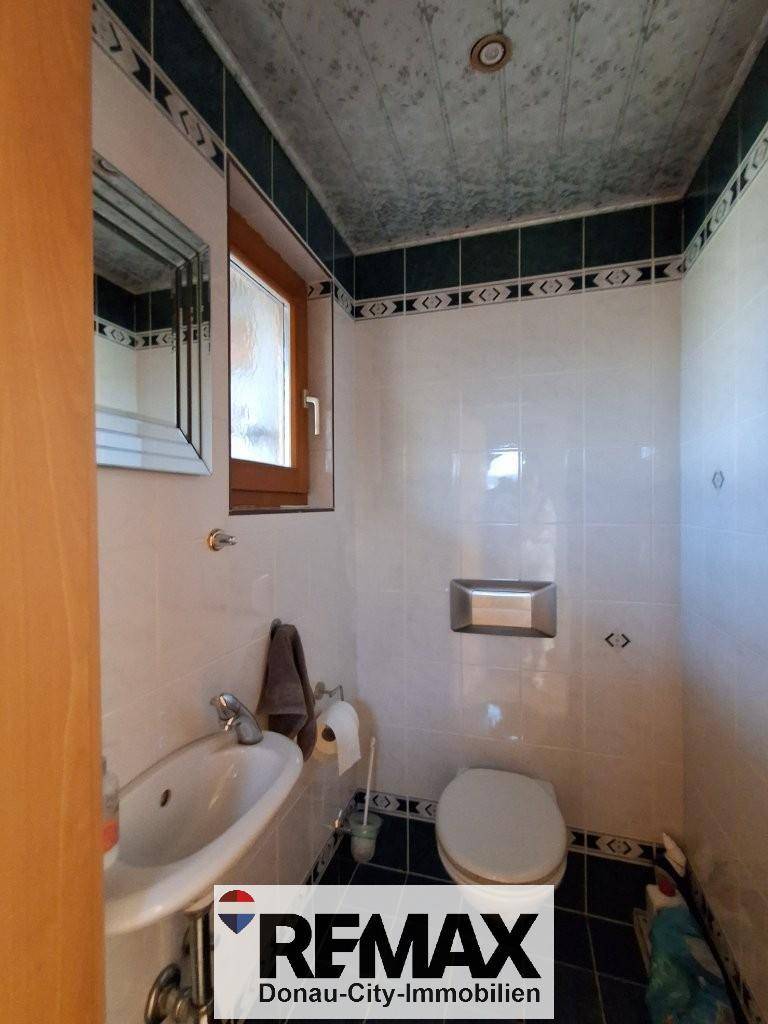 Kleines Gäste-WC mit gemusterten Fliesen, Waschbecken und wandhängendem WC, funktional und sauber.