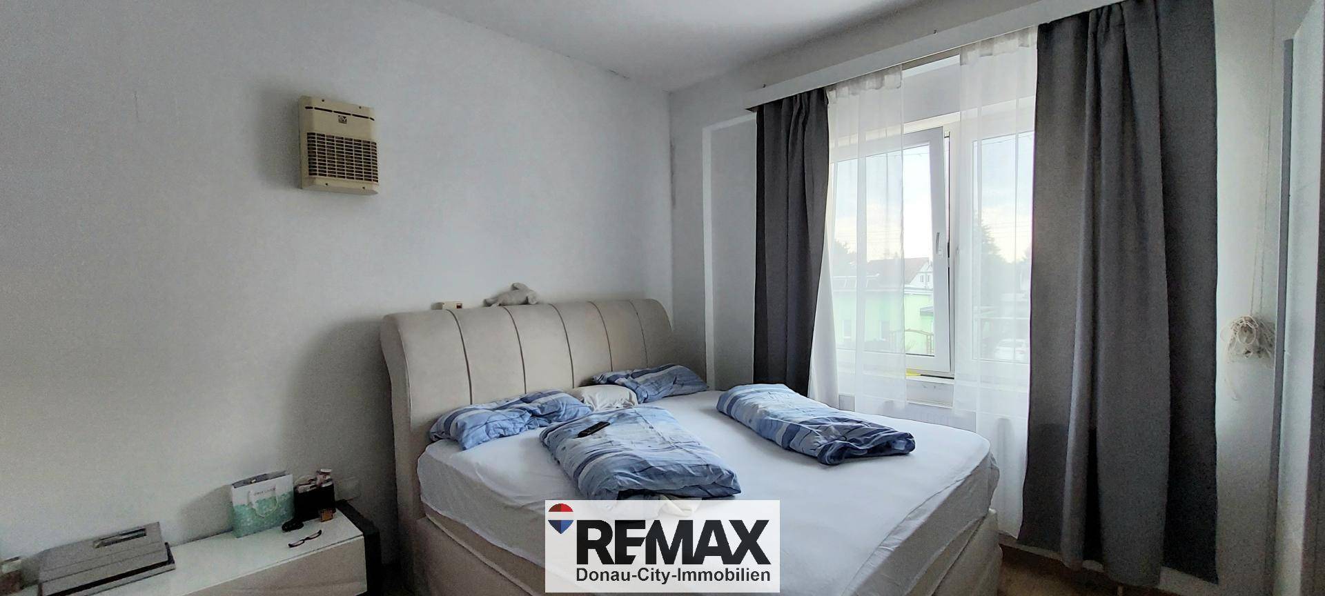 Schlafzimmer mit Doppelbett und Fenster, hell und einfach eingerichtet.