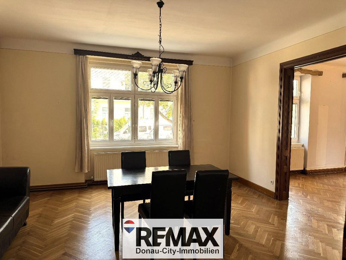 Heller Essbereich mit Holztisch, Parkettboden und einem großen Fenster mit Blick ins Grüne.
