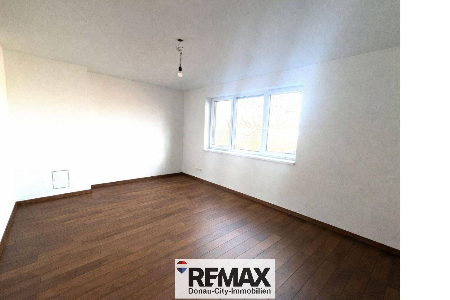 Helles Schlafzimmer mit Holzboden und einem großen Fenster, das viel Tageslicht bietet.