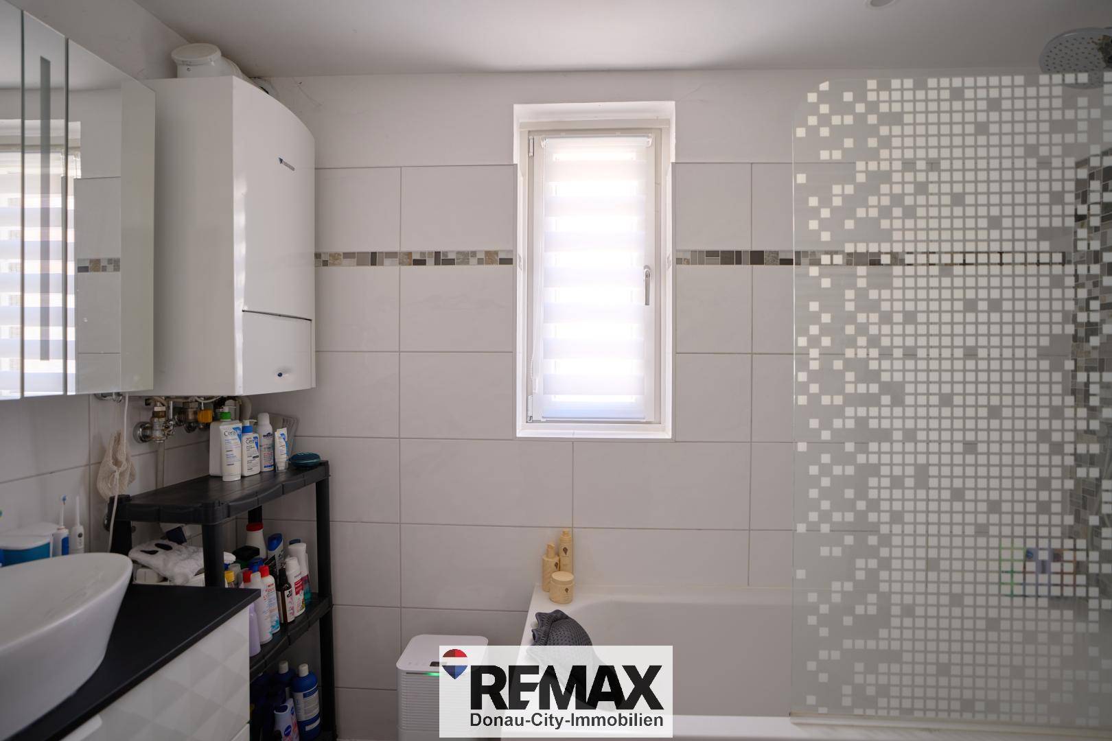 Helles Badezimmer mit Badewanne, Fenster und modernen Fliesen.