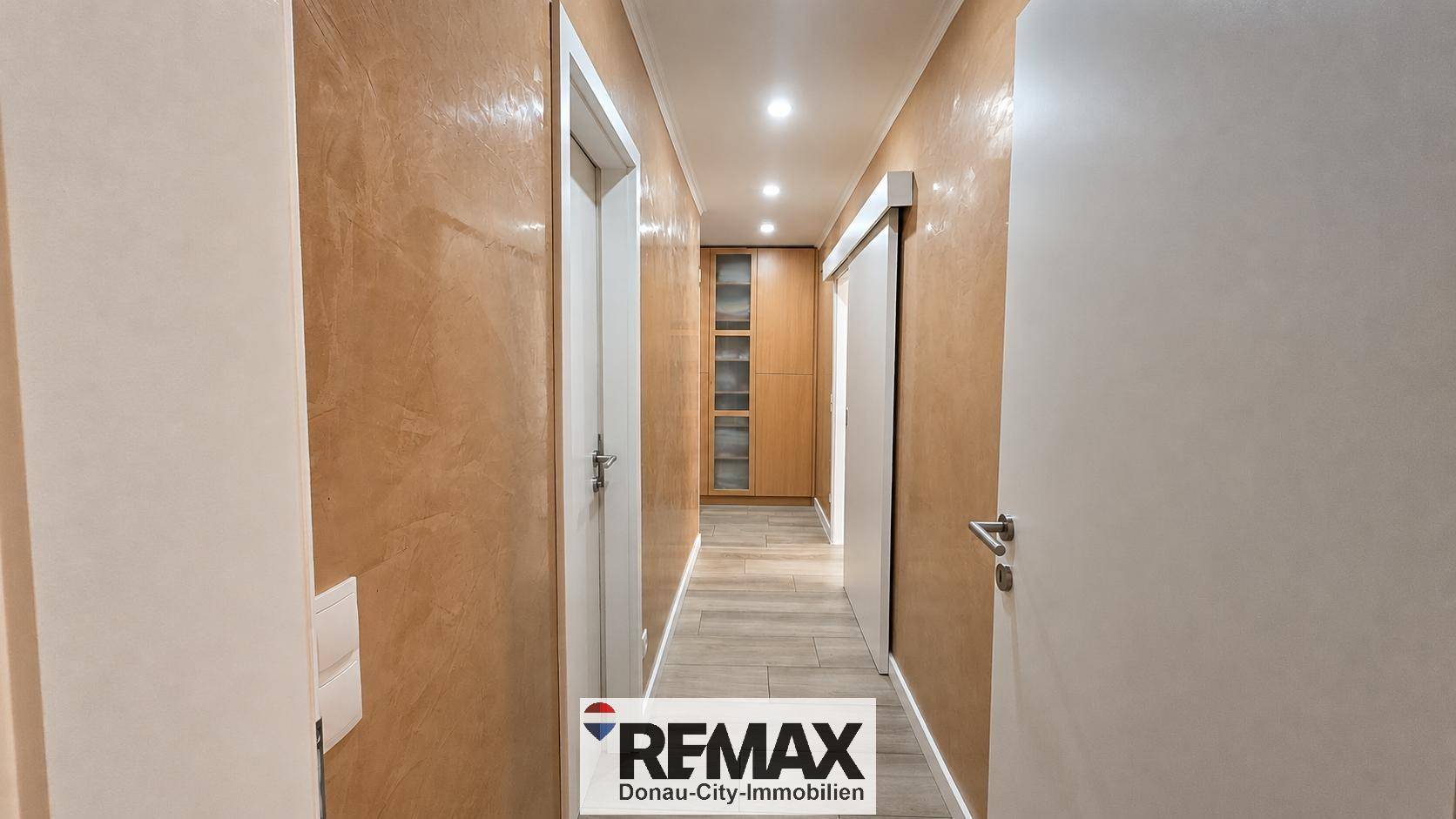 Heller Flur mit strukturierten Wänden, Einbauschrank und moderner Deckenbeleuchtung.