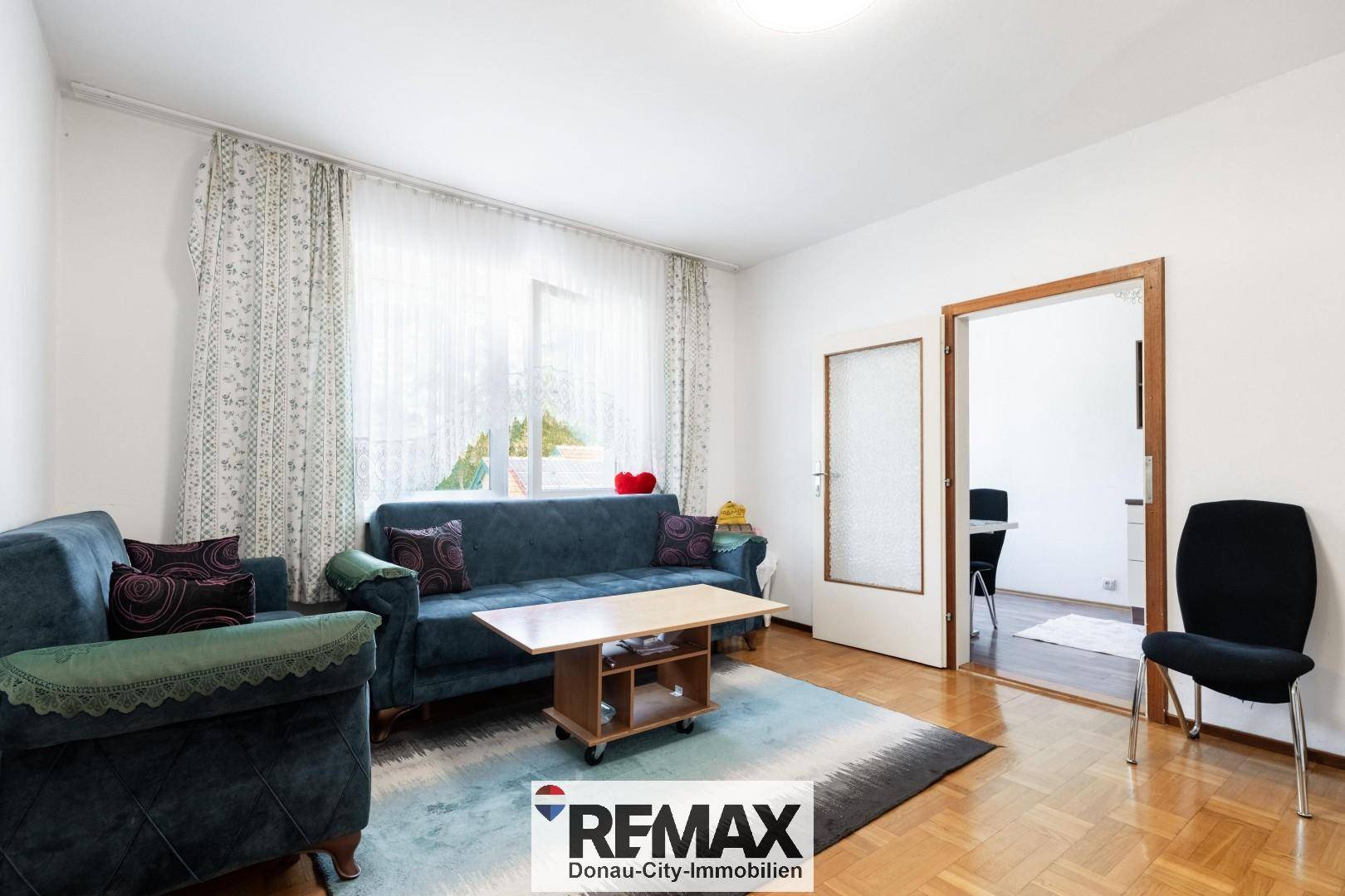 Helles Wohnzimmer mit blauen Sofas, Couchtisch und Parkettboden.