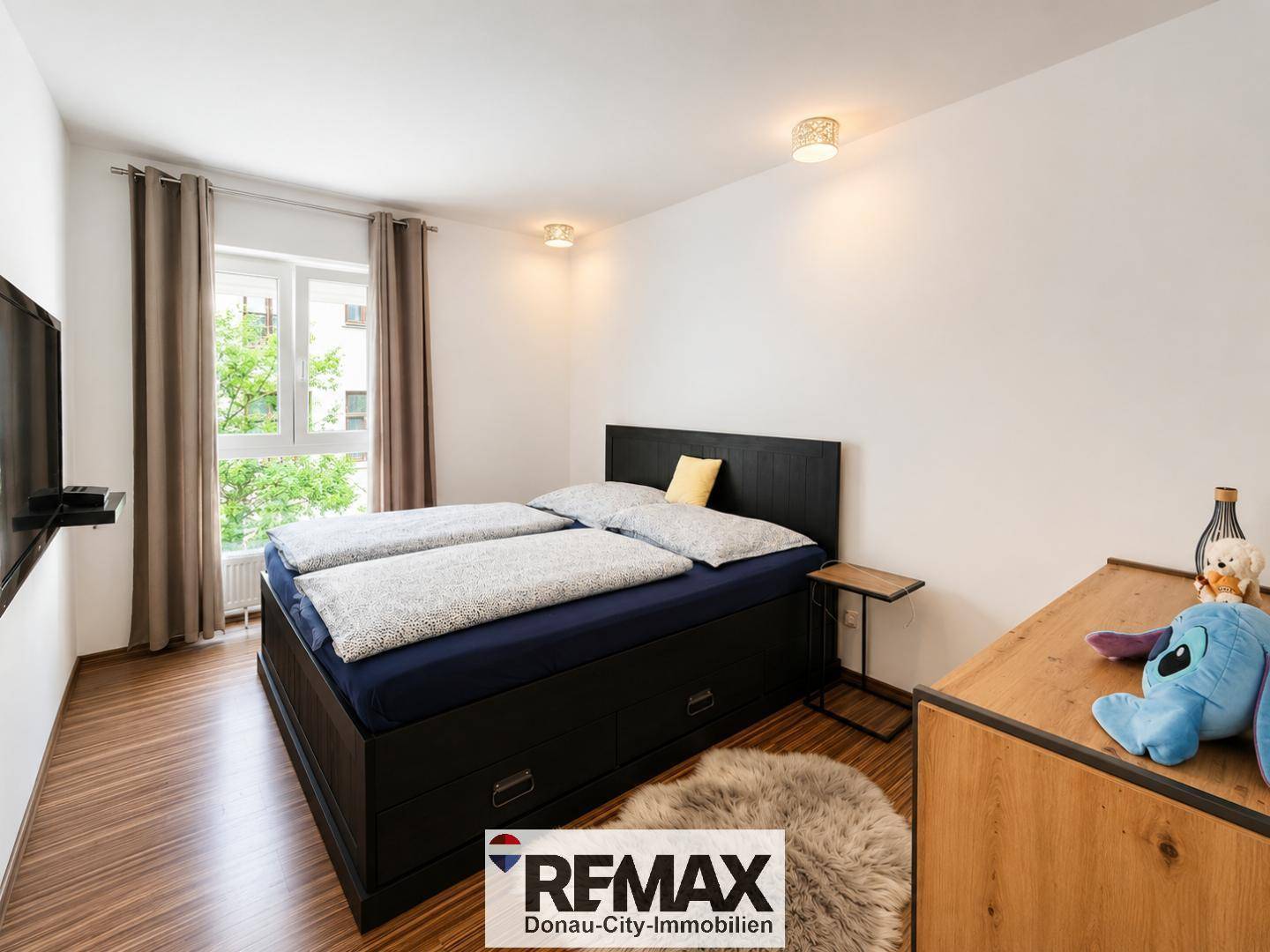 Gemütliches Schlafzimmer mit Doppelbett, Holzboden und Fenster mit Blick ins Grüne.