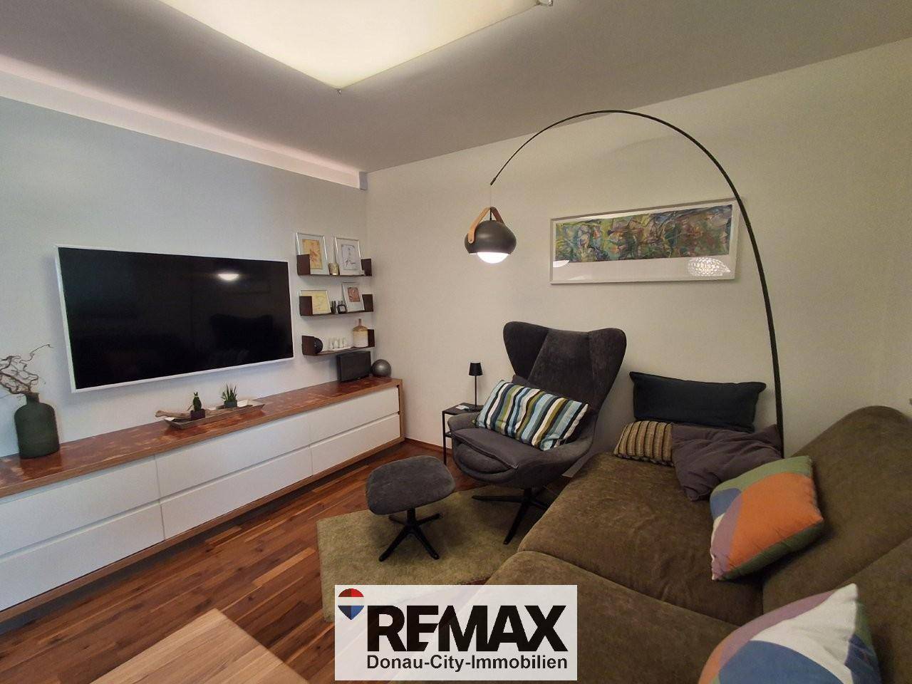 Gemütliches Wohnzimmer mit Holzboden, großem Sofa und modernem TV-Möbel.