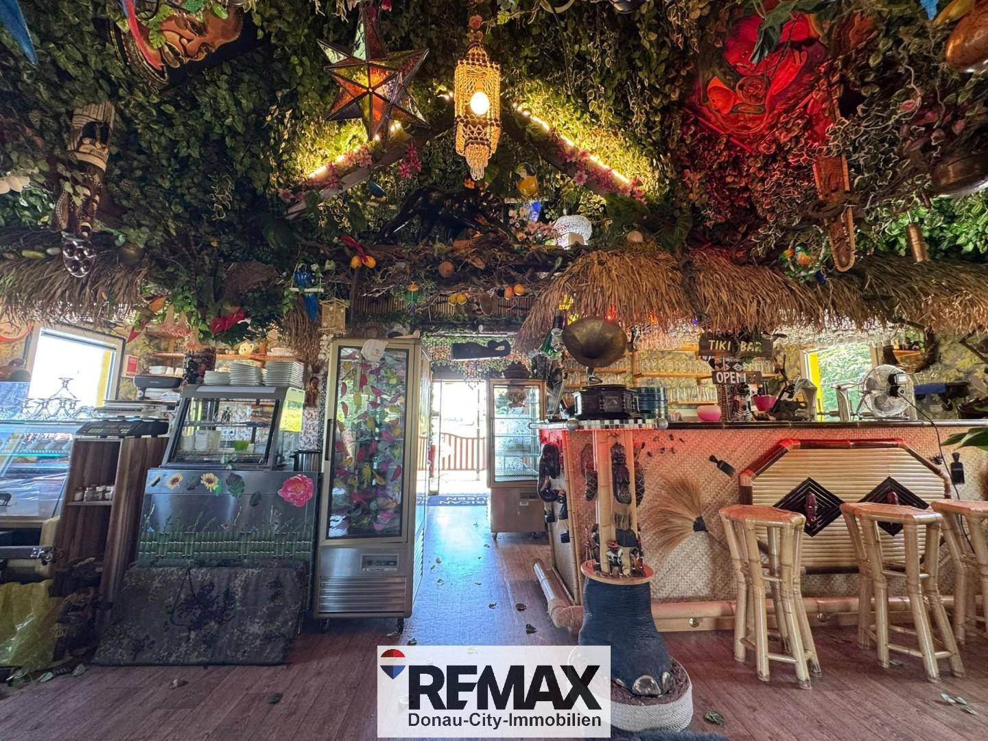 Innenansicht der Tiki-Bar mit Strohdach, Barhockern und exotischer Dekoration, sehr einladend gestaltet.
