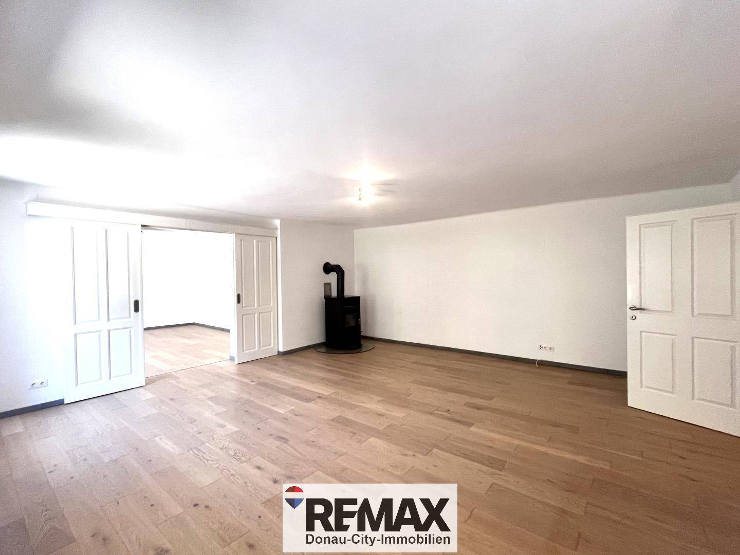 Gemütliches Wohnzimmer mit Holzboden und einem modernen Holzofen als Wärmequelle.
