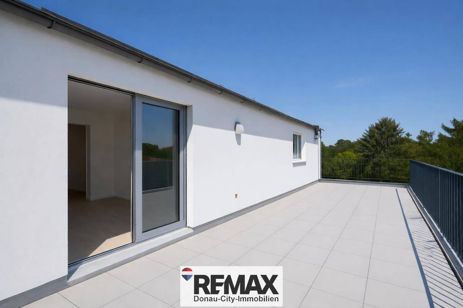 Weitläufige, leere Dachterrasse mit Fliesenboden und Blick auf die umliegende Natur.