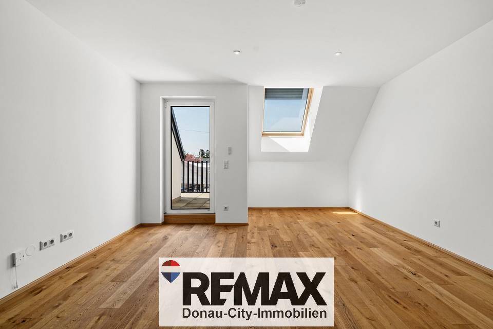 Geräumiges, helles Zimmer mit Holzboden, Dachfenster und direktem Zugang zu einem Balkon.