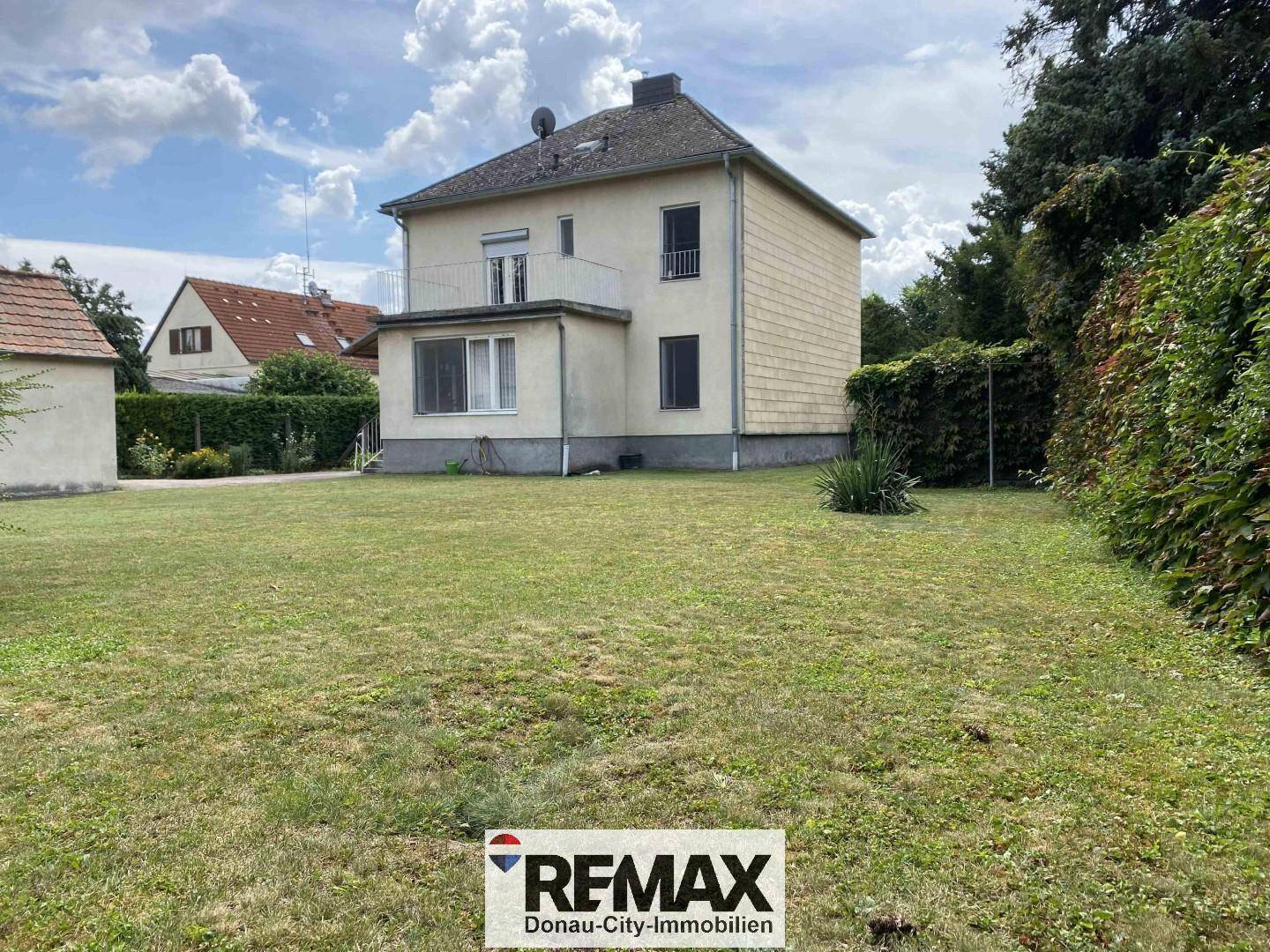 Seitenansicht des Einfamilienhauses mit großem Rasenbereich und angrenzendem Garten.