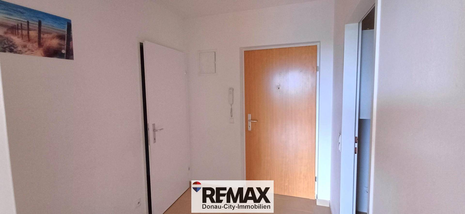 Eingangsbereich mit Holztür und weißen Innentüren, ausgestattet mit Gegensprechanlage.