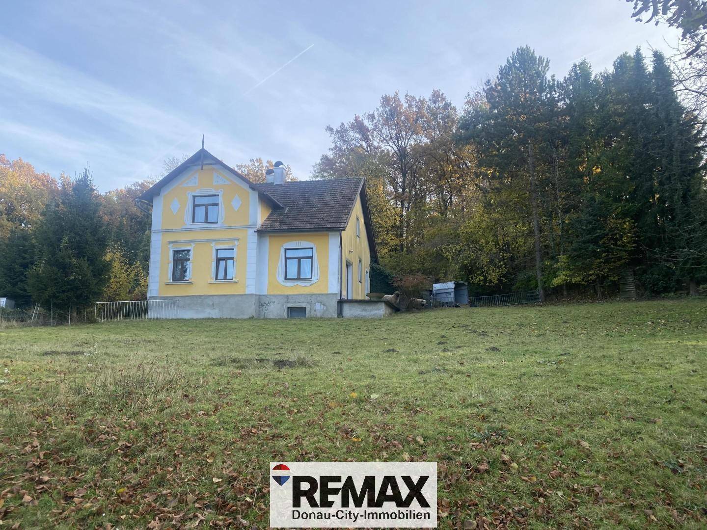 Weitläufiges Grundstück mit gelbem Landhaus und altem Baumbestand im Herbstlicht.