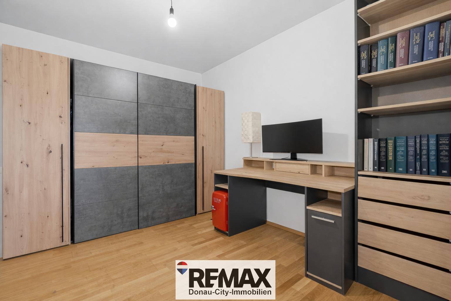 Schlafzimmer mit großem Kleiderschrank, Schreibtisch und Holzboden.