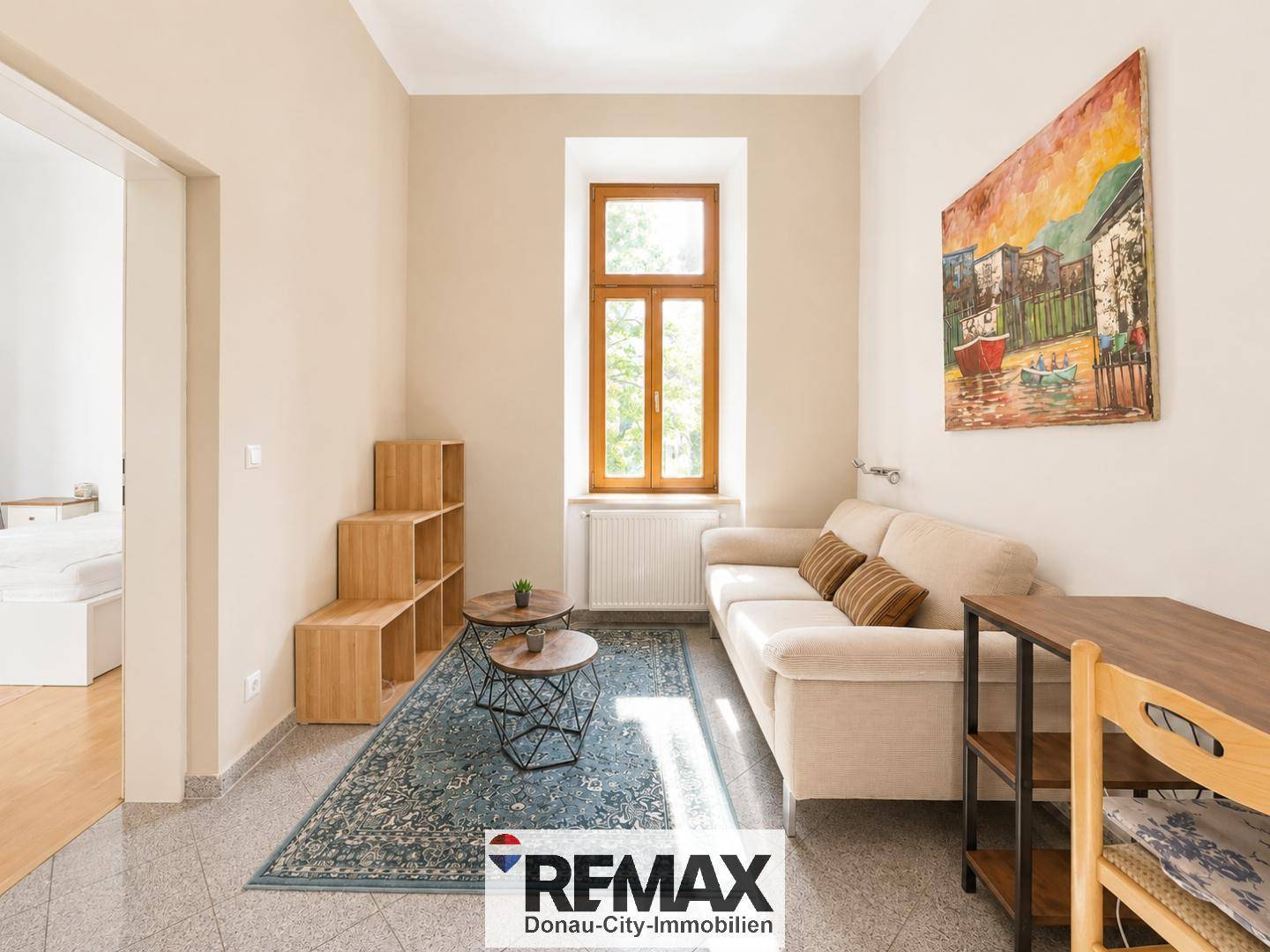 Gemütliches Wohnzimmer mit beigem Sofa, Holzelementen und einem Fenster, das den Raum erhellt.