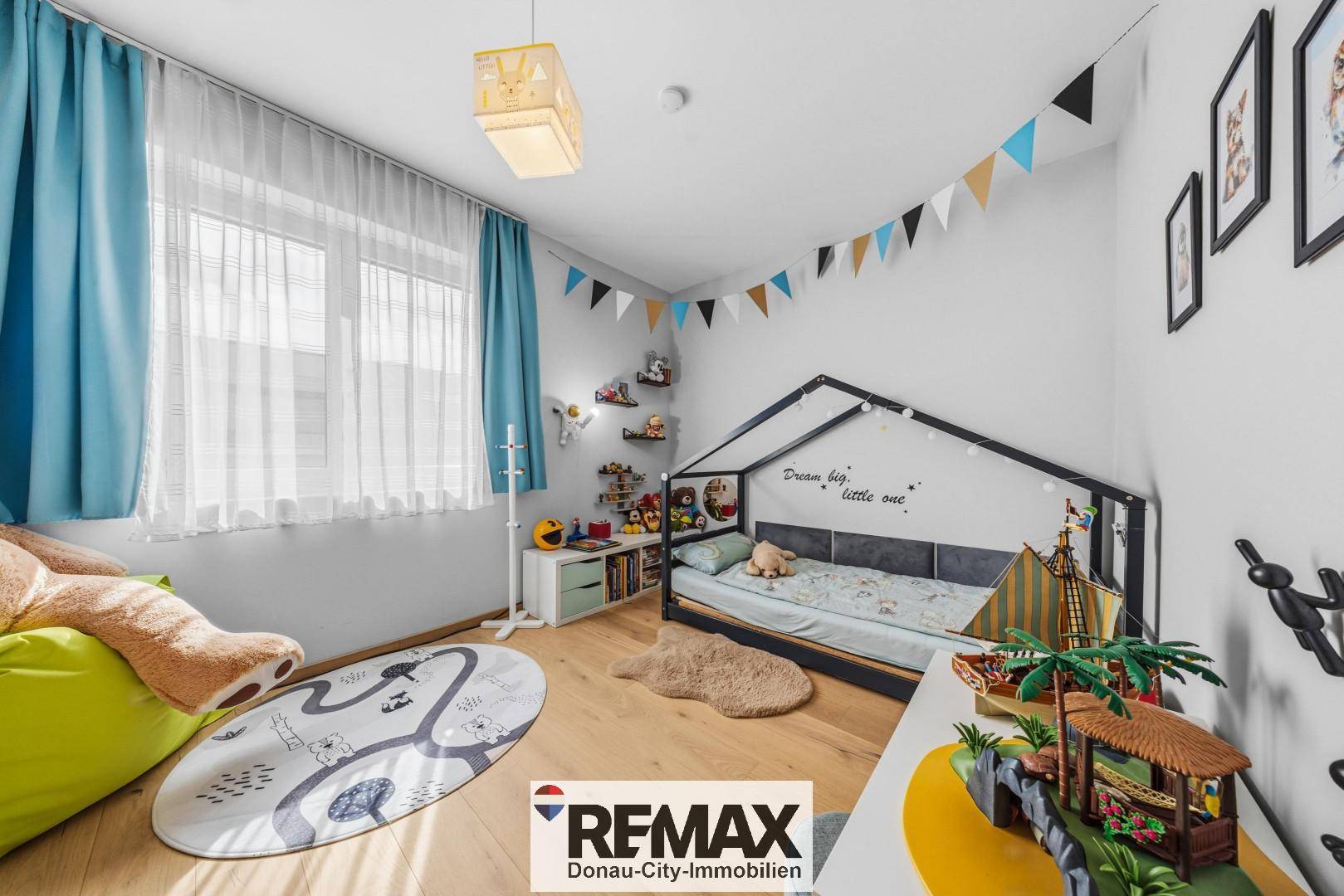 Helles Kinderzimmer mit Holzboden, Spielzeug und einem kreativen Bettgestell unter dem Fenster.