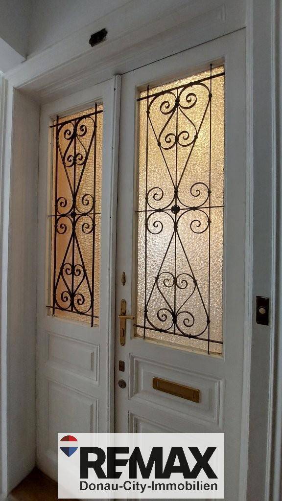 Detailansicht einer Eingangstür mit kunstvollen schmiedeeisernen Gittern in den Glaseinsätzen.