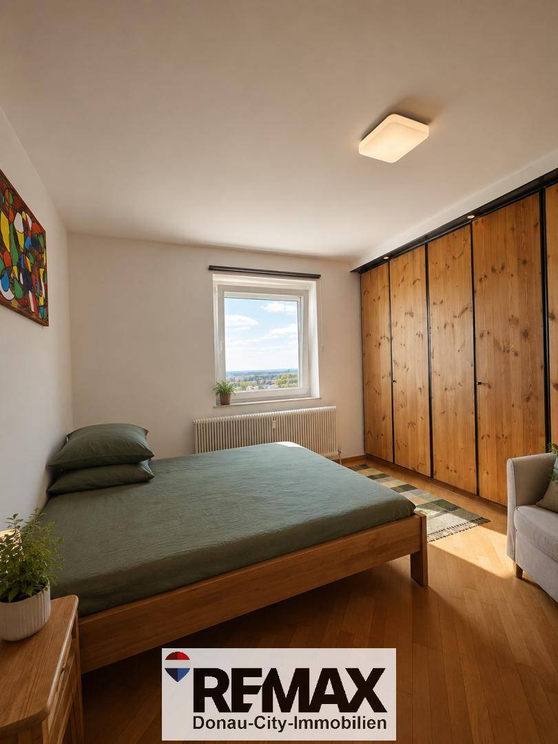 Gemütliches Schlafzimmer mit Holzbett, großem Holzschrank und Fenster mit Ausblick.