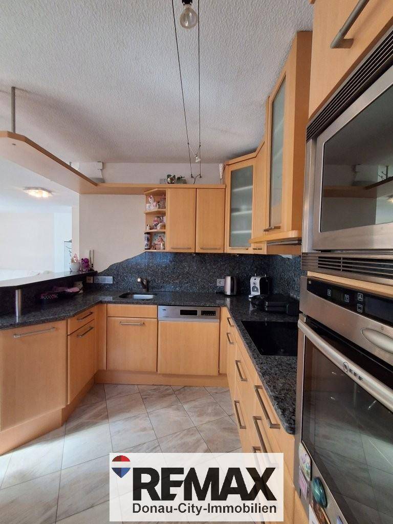 Voll ausgestattete Küche mit Holzfronten, dunklen Granitarbeitsplatten und modernen Einbaugeräten.