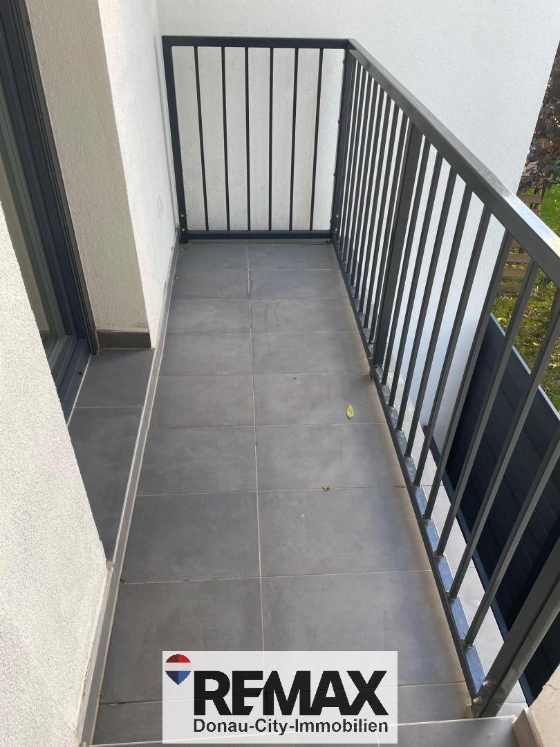 Gefliester Balkon mit Metallgeländer und Blick ins Grüne.