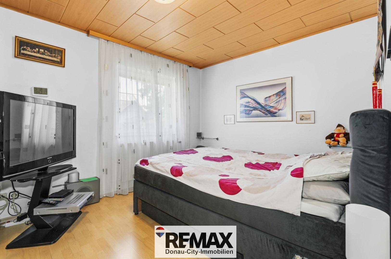 Gemütliches Schlafzimmer mit Holzbalkendecke, Doppelbett und Fenster.