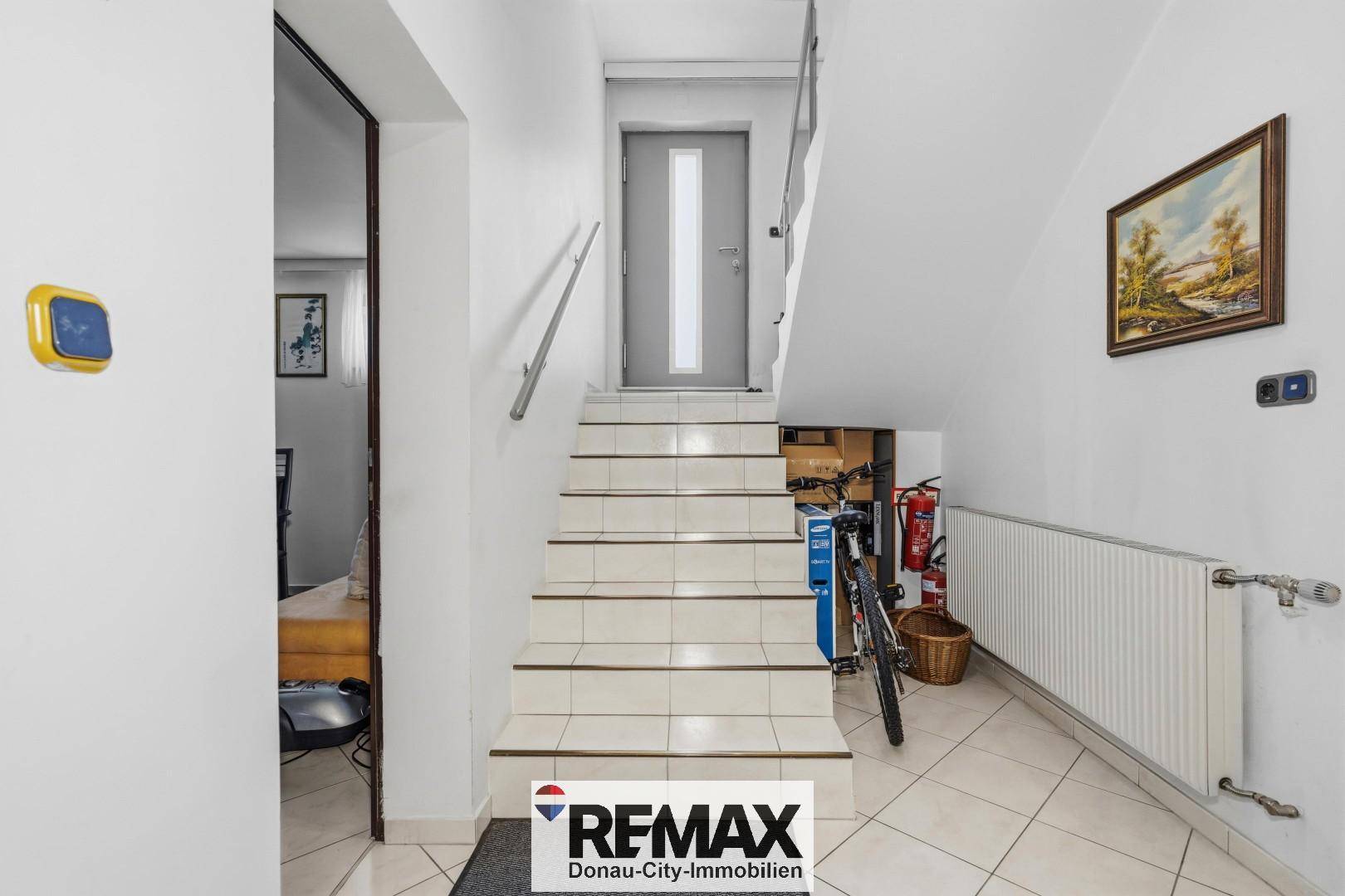 Treppenabgang zum Kellerbereich mit Fliesenboden und Stauraum unter der Treppe.